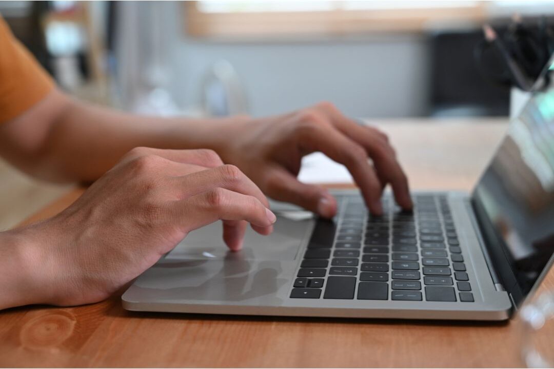 close up view of a woman typing on a laptop keyboard to interlink blog posts
