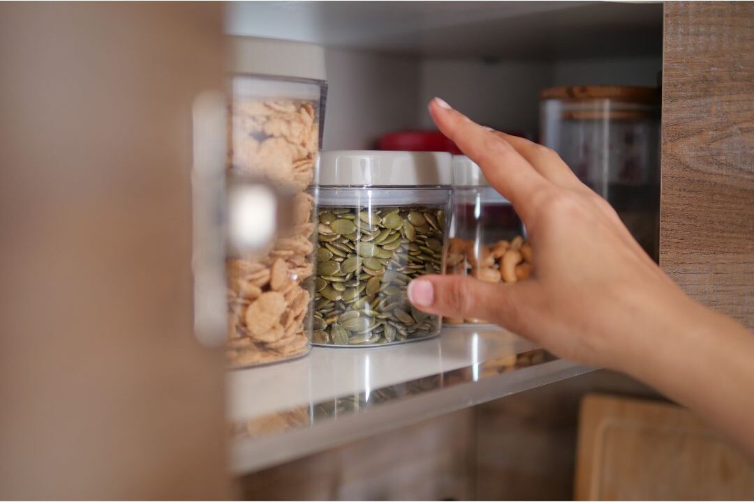 organized low pantry shelf with clear jars of healthy snacks for self-serve children