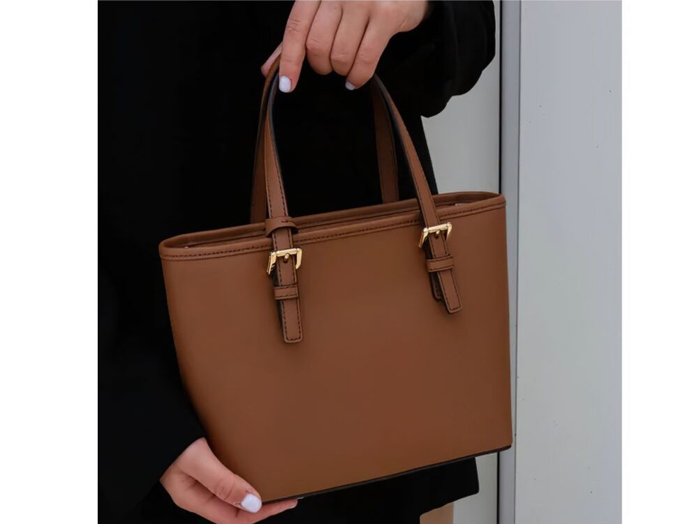 chic woman holding minimalist smooth brown leather handbag without logos demonstrating quiet luxury
