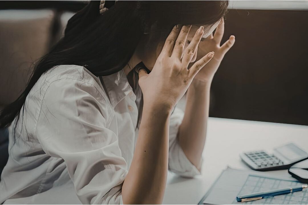 discouraged woman sitting on a couch looking at a paper feeling task dread