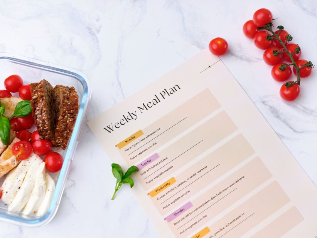 weekly meal planner notepad next to fresh vegetables demonstrating structured meal systems
