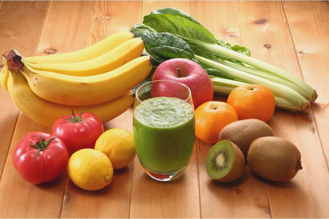 fresh whole vegetables and fruits arranged on a wooden cutting board