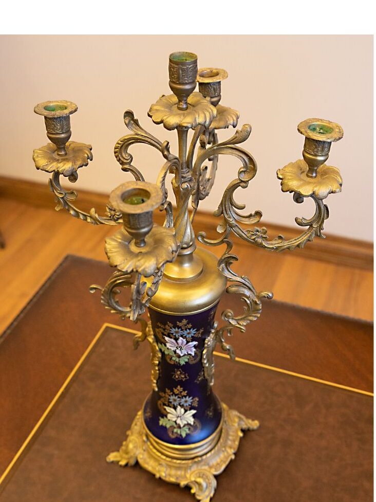 woman carefully inspecting vintage brass candleholder at market proving that elegant living doesn't mean expensive