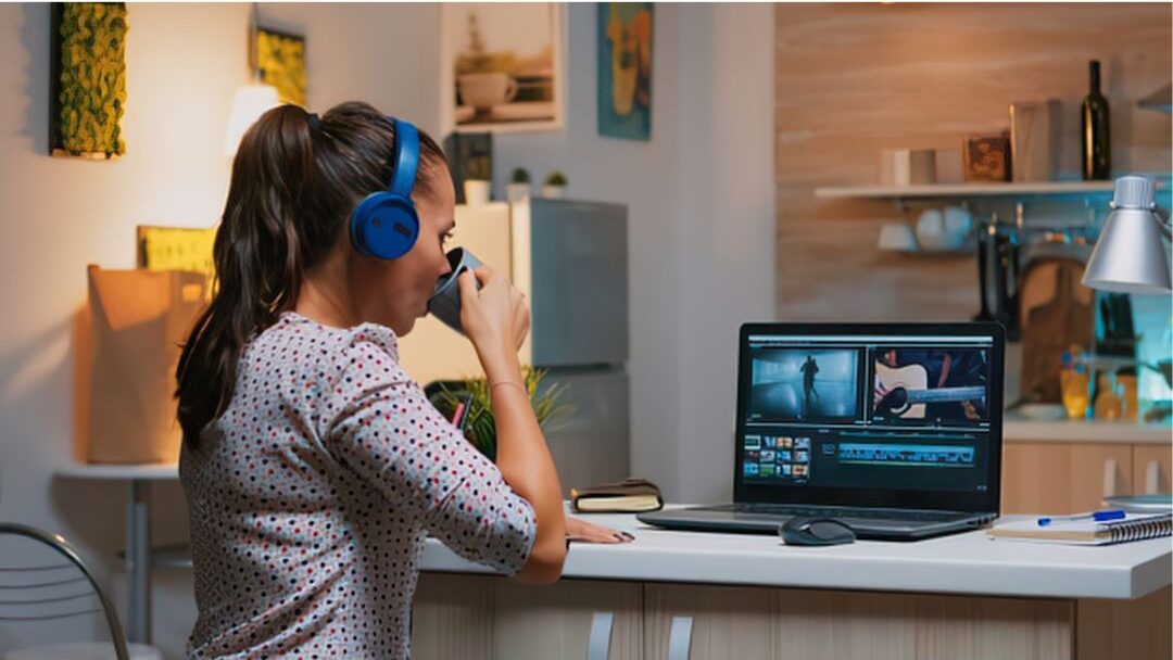 woman reviewing a laptop screen with a mug in a cozy kitchen setting