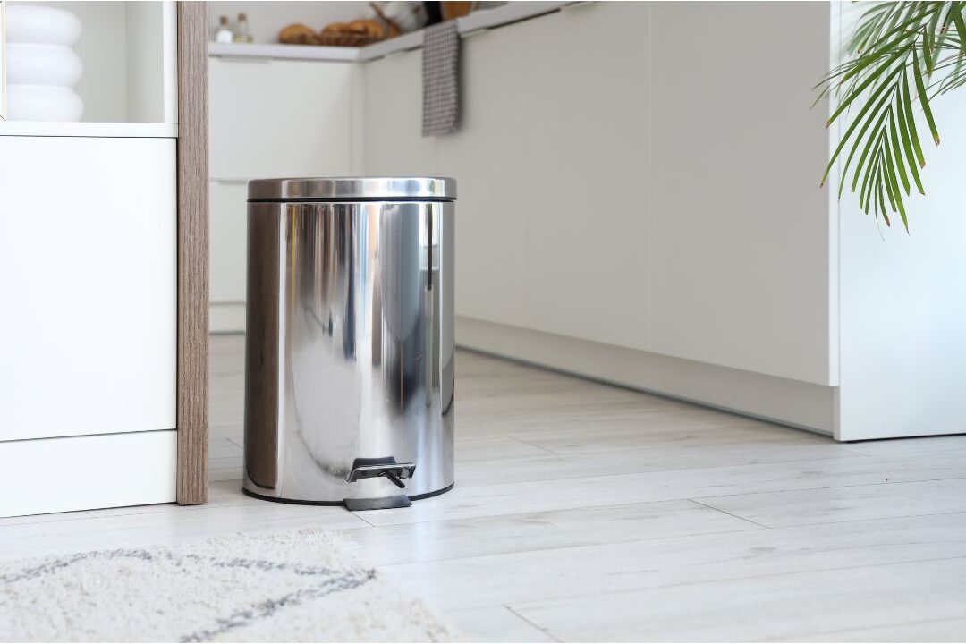 clean minimalist kitchen with empty stainless steel trash can illustrating home systems that practically run themselves