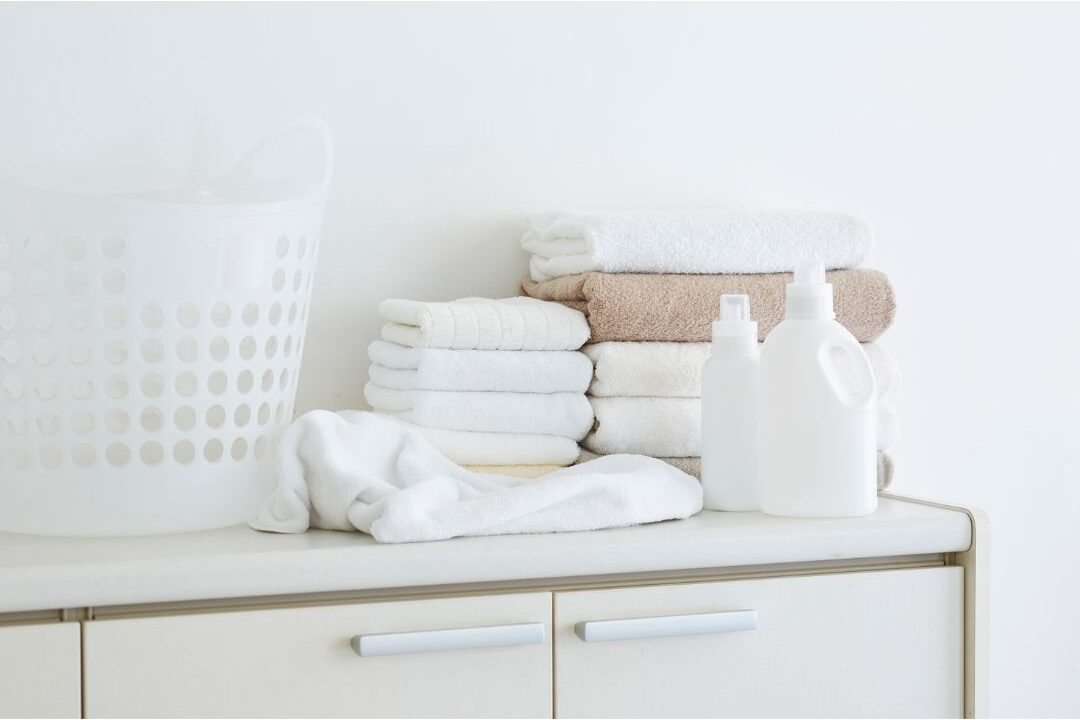 stacked clean folded white towels in laundry room illustrating daily laundry systems