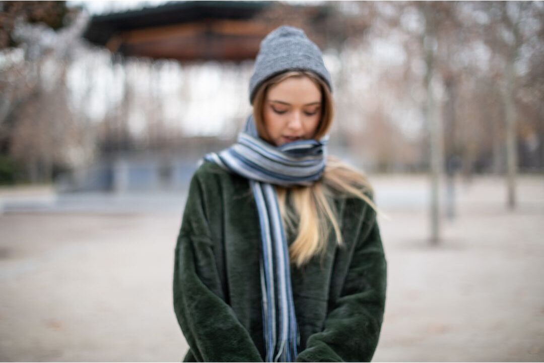 woman wrapping soft cream cashmere scarf around coat collar illustrating luxury textiles