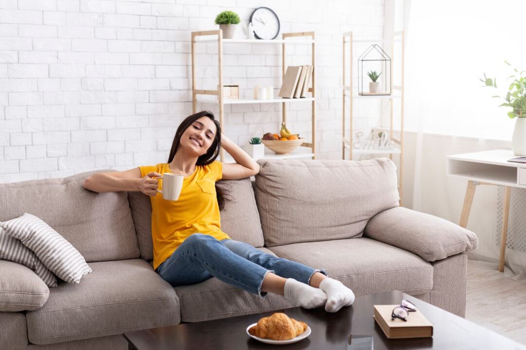 woman sitting on a comfortable sofa enjoying a peaceful cup of tea at home