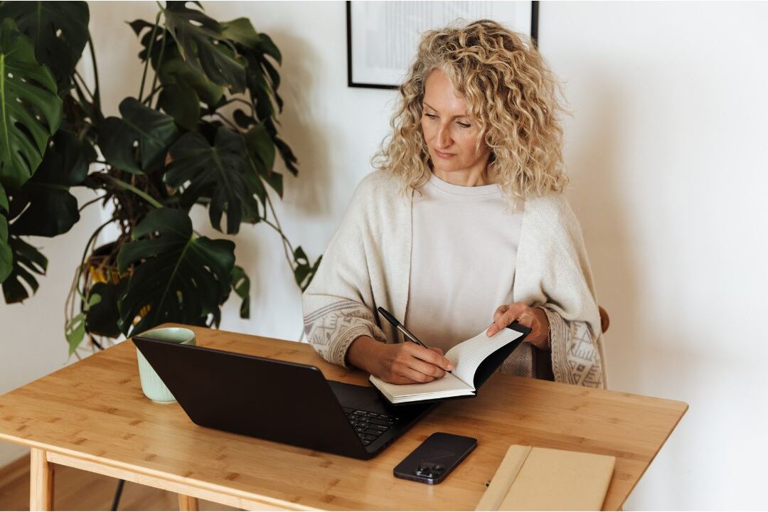 peaceful mother looking at notebook at bright kitchen table discovering the productivity rule every mom should know