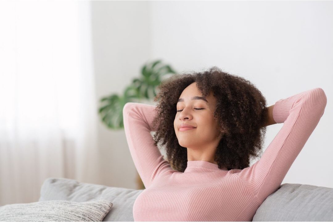 serene woman relaxing on comfortable armchair with closed eyes enjoying emotional peace