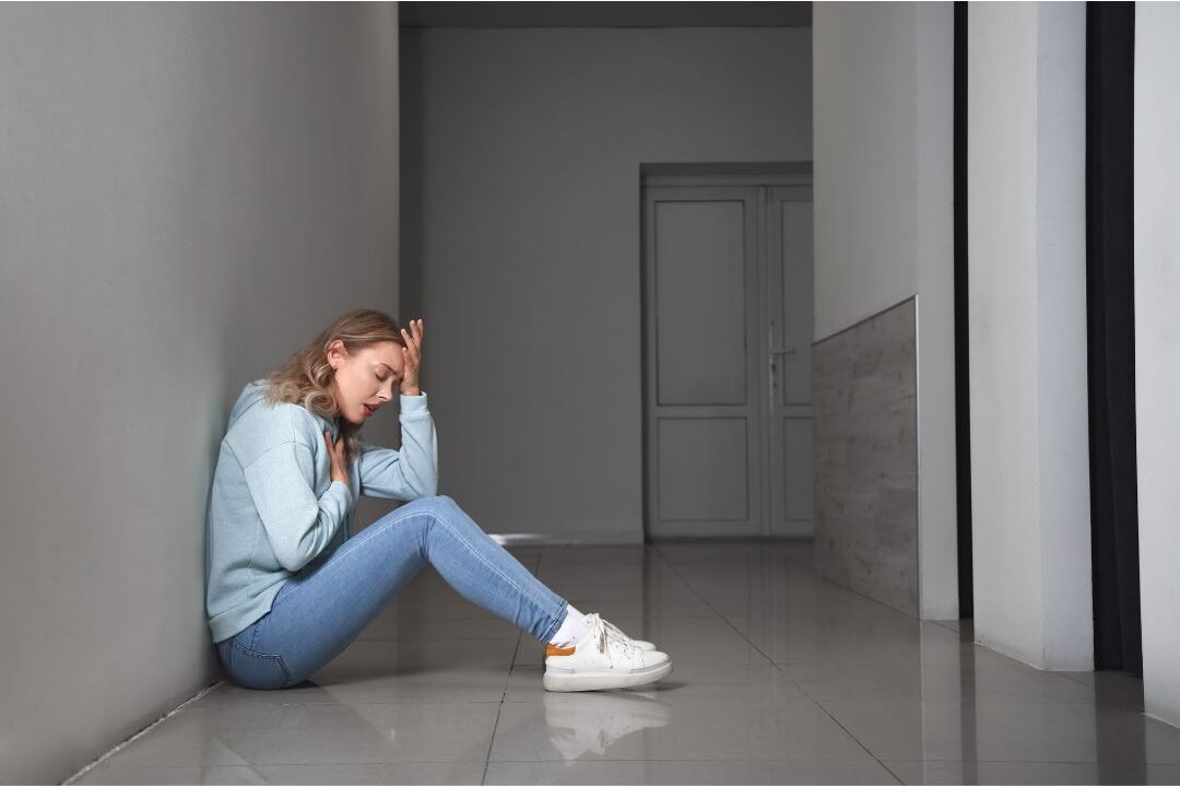 stressed woman sitting on the floor taking a breath showing signs your body needs rest