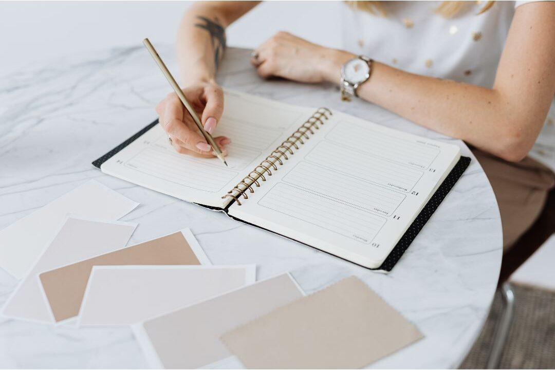 woman writing in paper daily planner at bright desk taking control of schedule boundaries