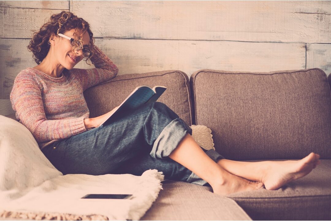 relaxed woman relaxing on sofa reading a book enjoying reclaimed time