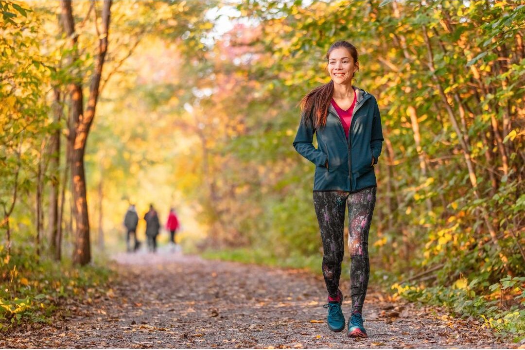 woman walking through a quiet green park surrounded by trees