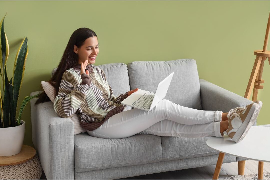woman video chatting on a laptop sitting comfortably in a living room discussing passive income streams that actually still work