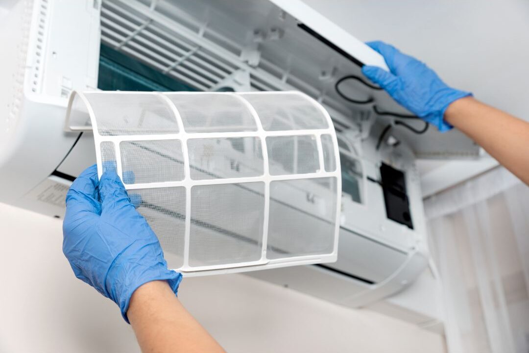 man changing air filter in home wall ventilation unit showing home systems that practically run themselves