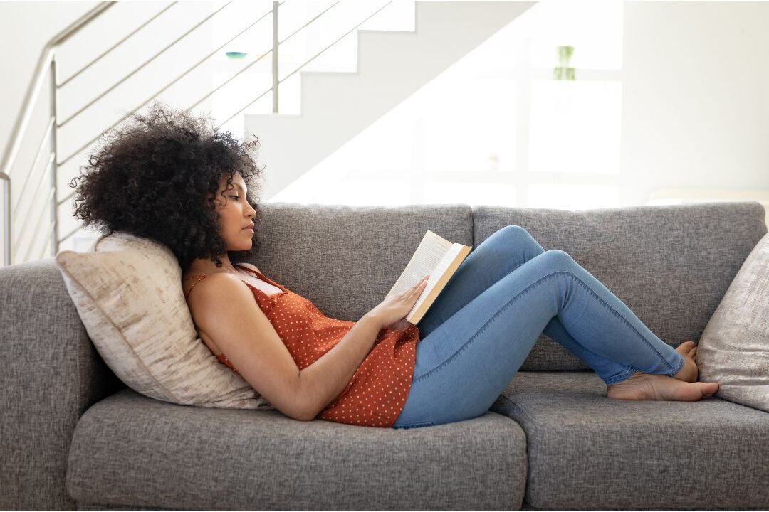 relaxed woman resting on sofa with book and sunbeam illustrating restorative rest
