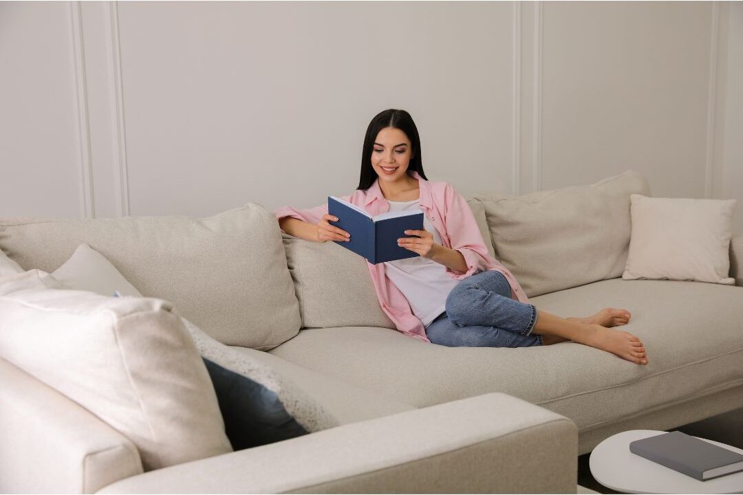 woman reading book on cozy sofa in relaxed modern living room navigating hidden challenges nobody warns moms about