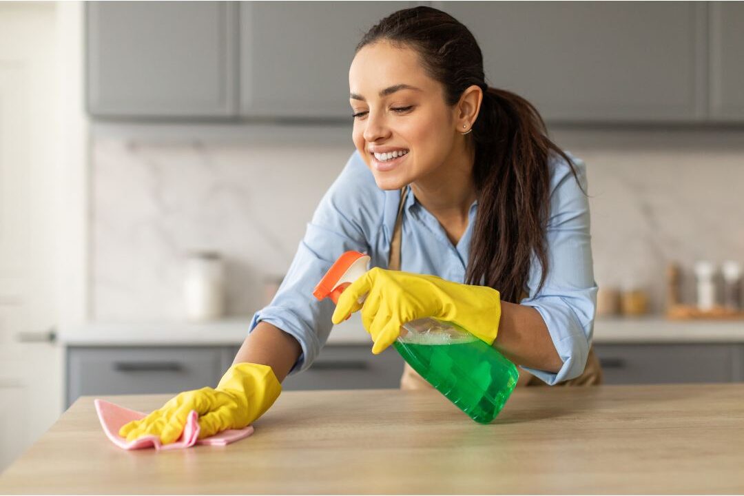 woman wiping down marble kitchen counter with microcloth illustrating zone cleaning routines