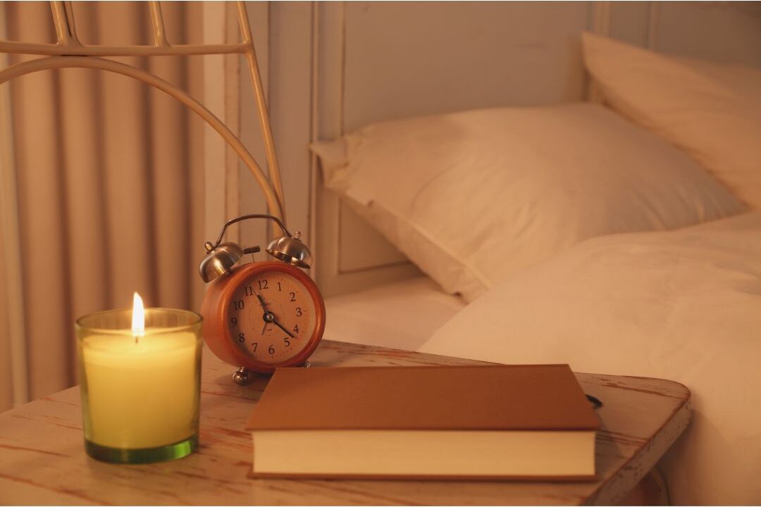 warmly lit bedroom nightstand with a book showing evening prep
