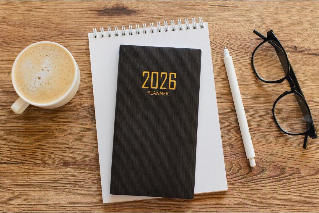 calendar planner sitting on wooden desk next to coffee mug showing intentional planning