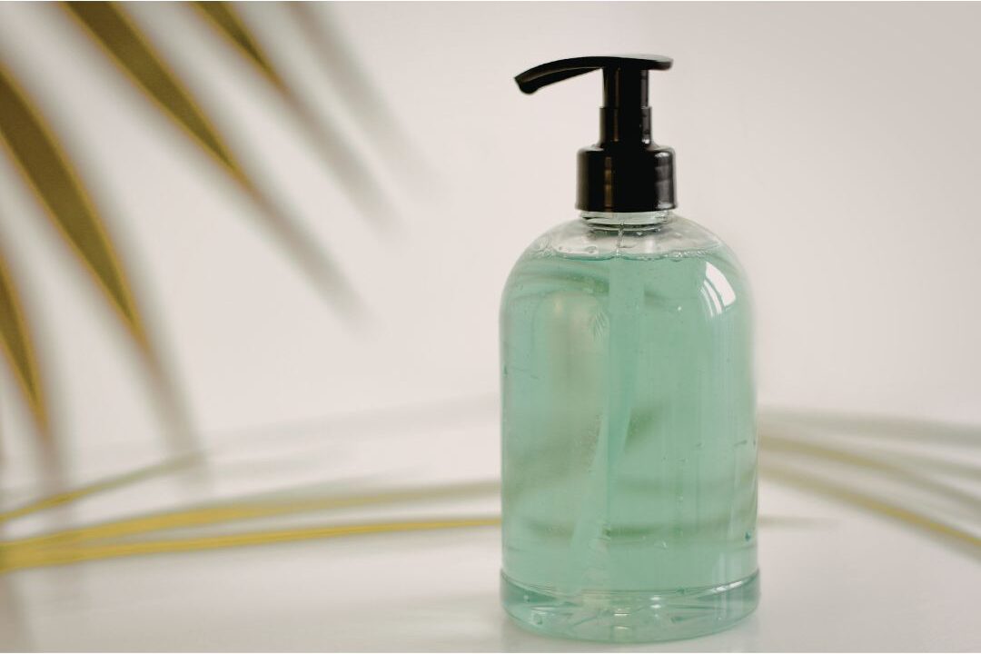 glass pump bottle with natural hand soap on neat bathroom counter illustrating decanted beauty