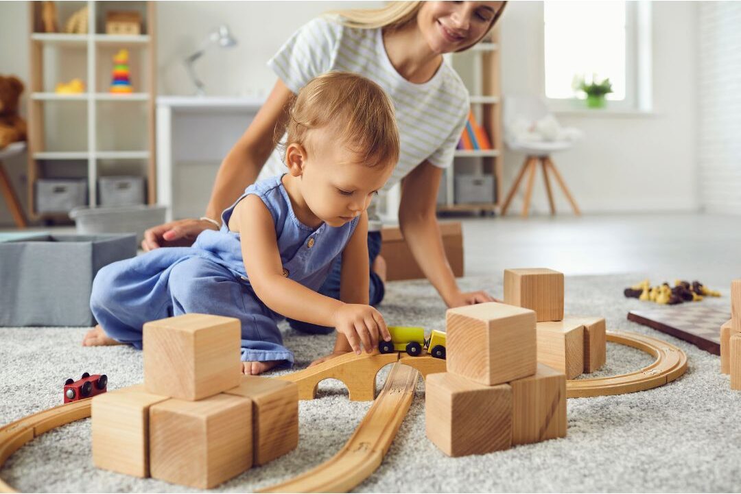 child playing quietly with wooden blocks on rug near mom illustrating independent play