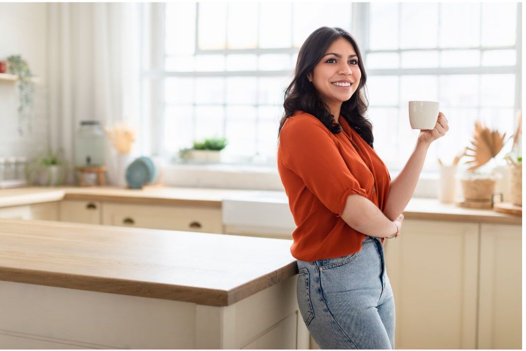stylish woman holding a mug in a modern kitchen reflecting aesthetic lifestyle pressure