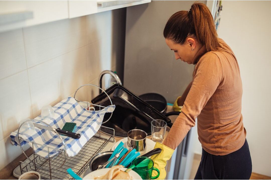 woman looking at cluttered kitchen counter thoughtfully contrasting online trends with domestic reality