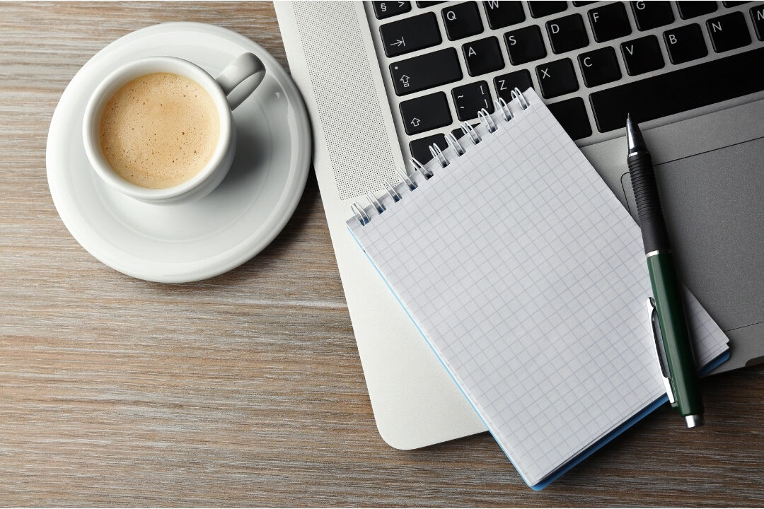 top down view of paper notebook planner beside laptop and coffee avoiding 10 mistakes that are killing your productivity at home
