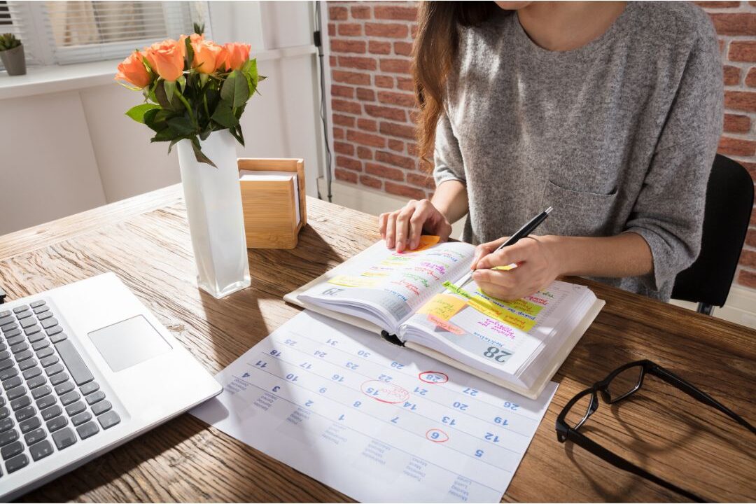 woman setting up a calendar planner on a clean desk space