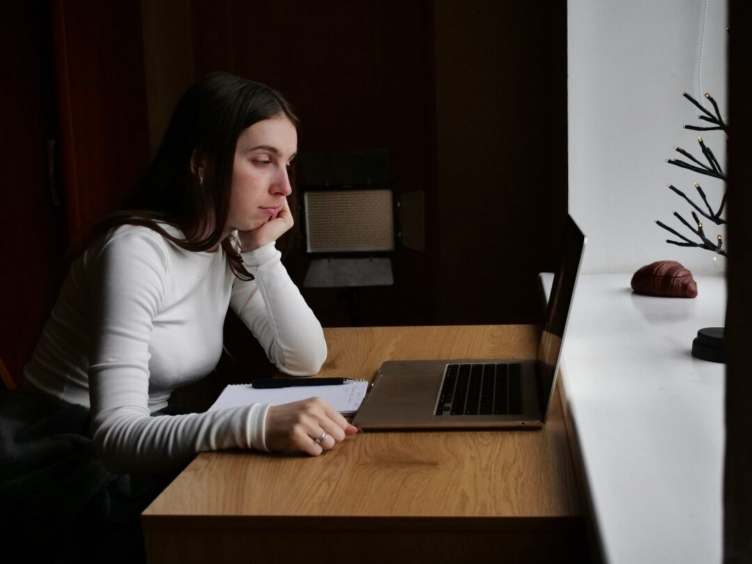 woman working calmly on laptop at a clean wooden desk focusing on daily work blocks