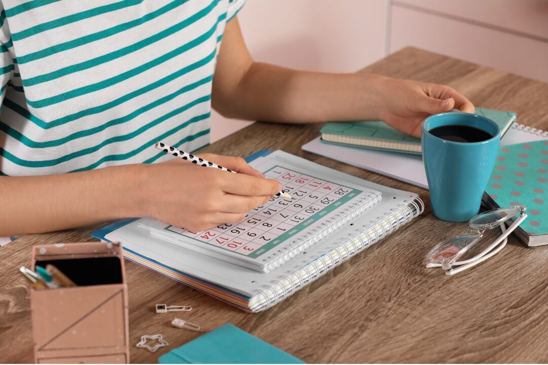 woman planning weekly calendar with coffee cup on clean wooden table showing weekly structure