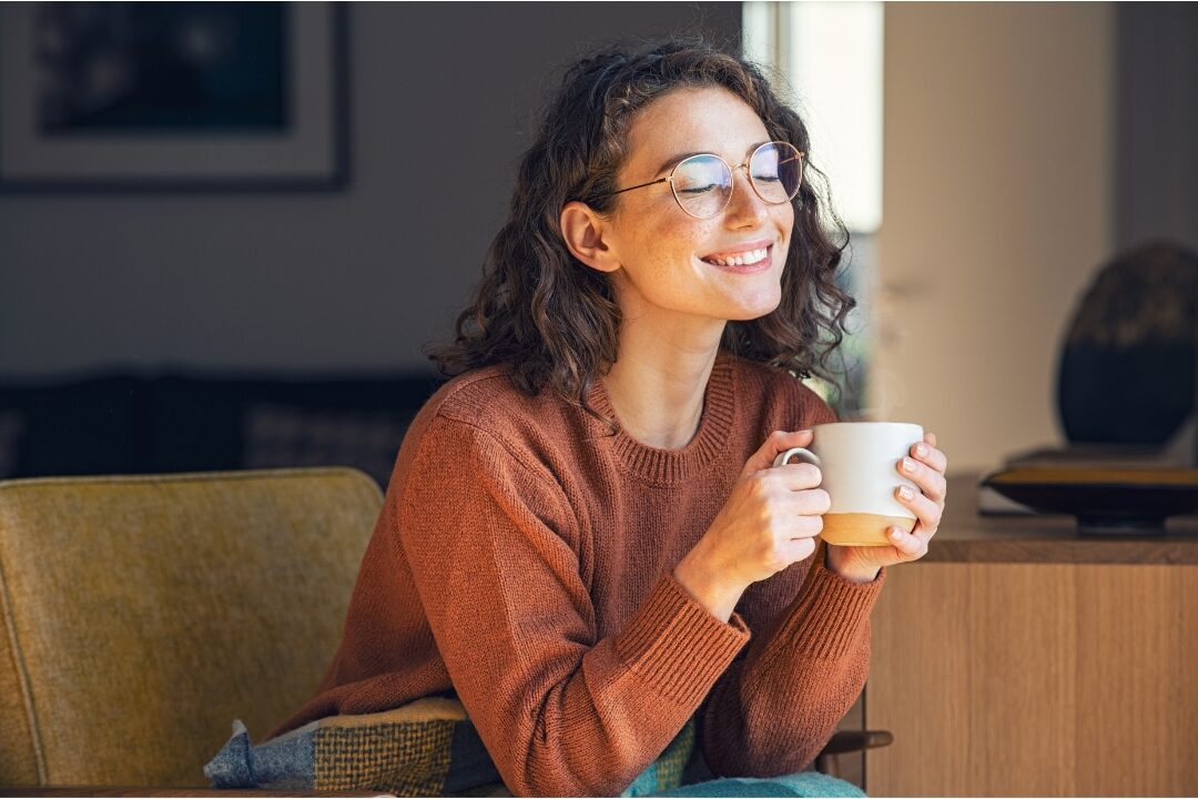 happy woman enjoying tea in a clean minimalist dining room showing sustained home organization