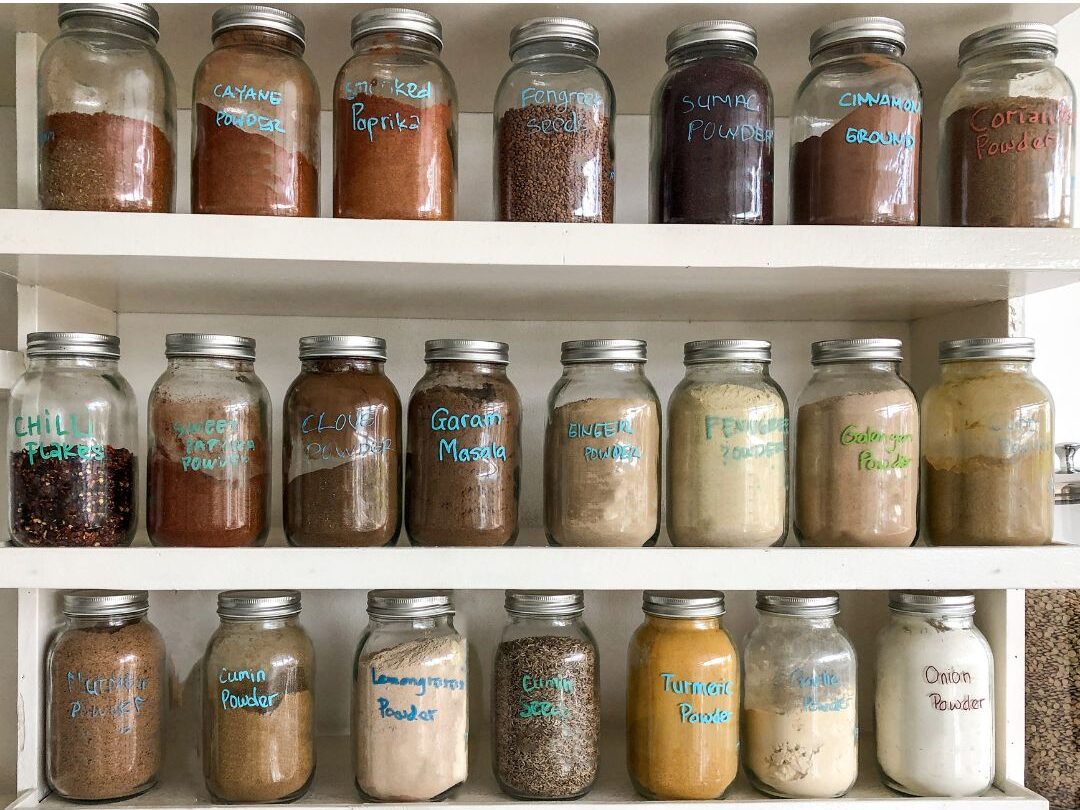 organized kitchen pantry with labeled glass jars and wooden shelves illustrating organized home systems