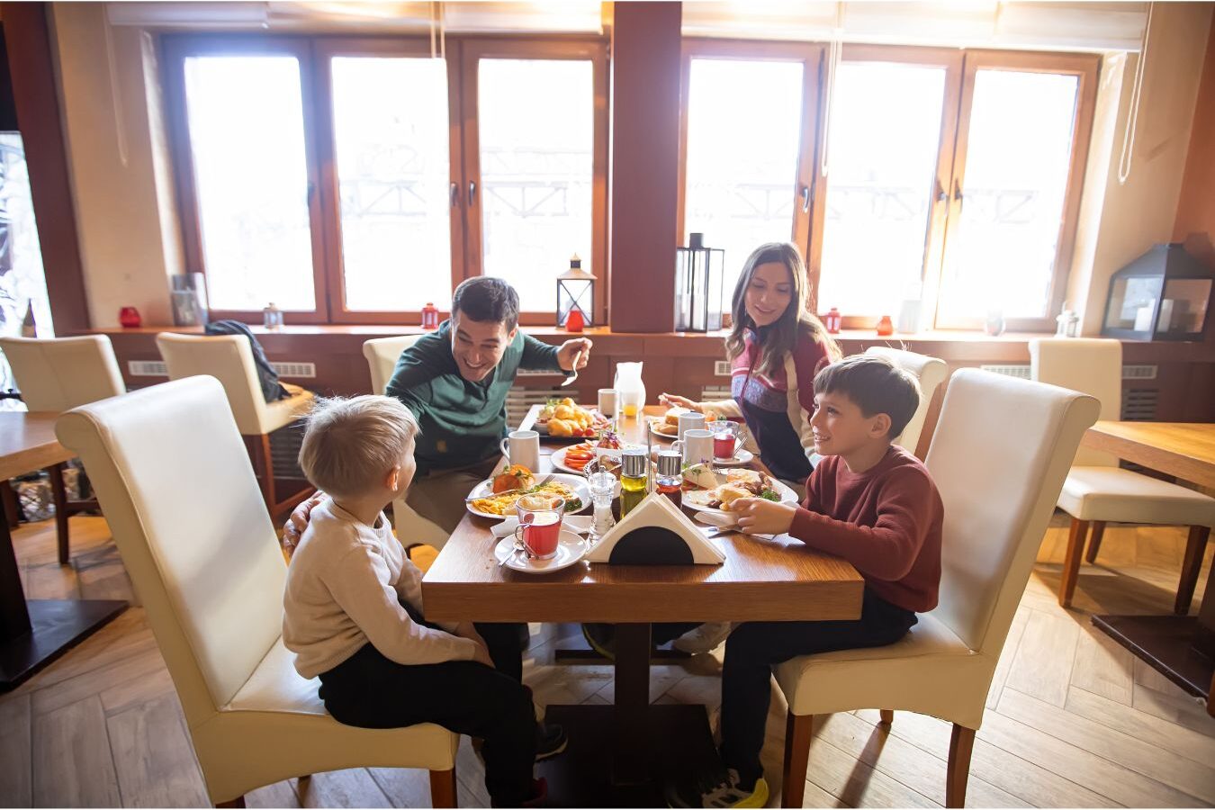 cheerful mother sharing warm breakfast with children at dining table enjoying calm family time