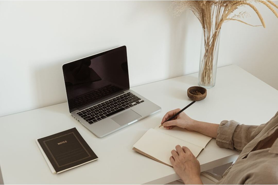 woman writing pricing strategy notes on a white desk to avoid underpricing her work