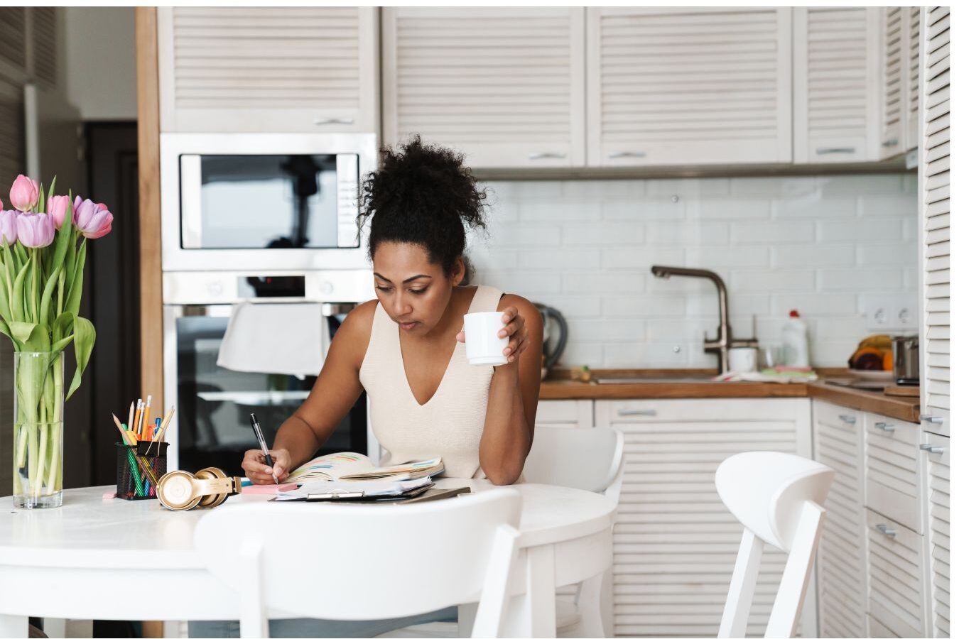 woman writing in planner at clean sunlit kitchen table learning how to get more done before breakfast