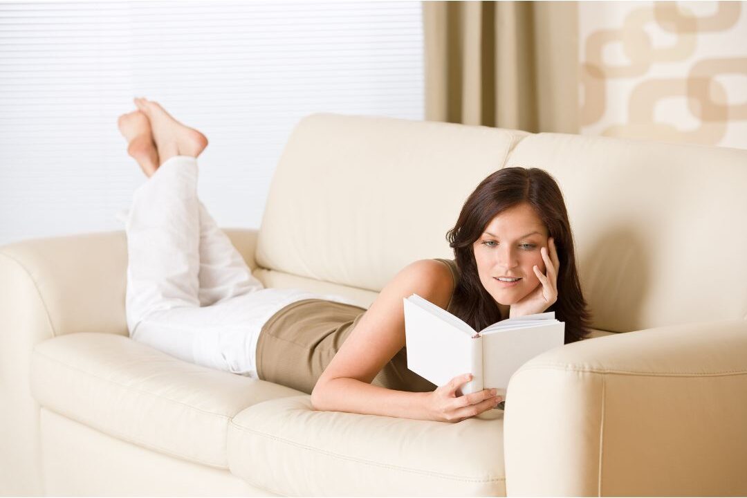 woman lounging peacefully on a sofa holding a book without pressure