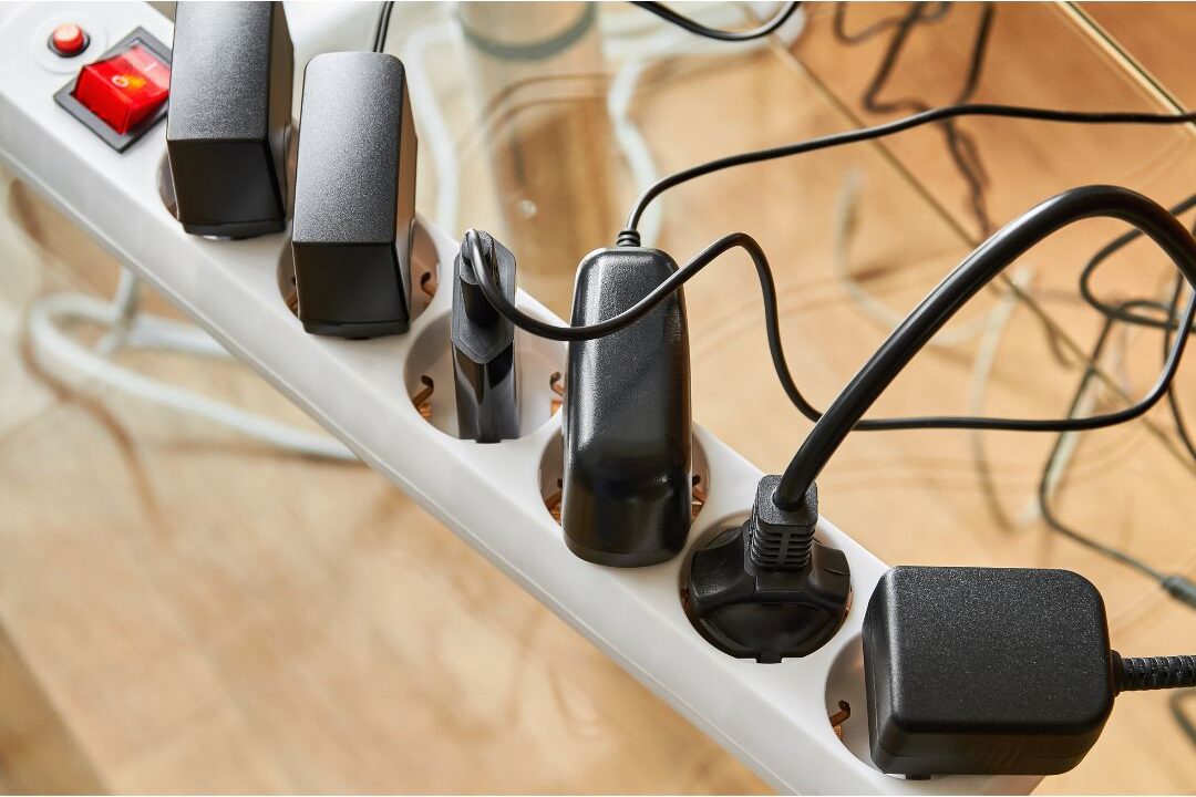 power strip plugged into a wall with multiple electronic cords drawing standby power