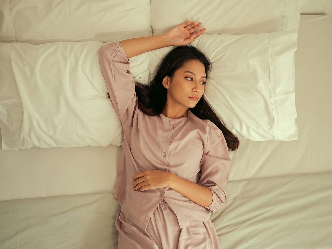 woman lying in bed staring at the ceiling experiencing night insomnia