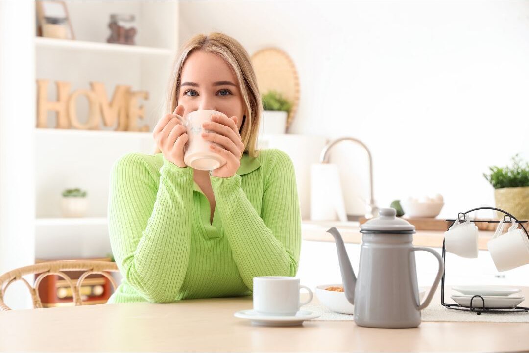 woman enjoying tea at wooden kitchen table filled with natural sunlight illustrating domestic joy