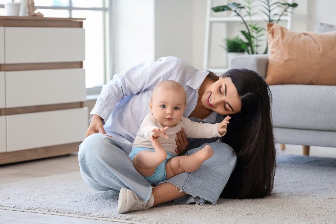 mom sitting on living room floor smiling with her young child showing domestic peace