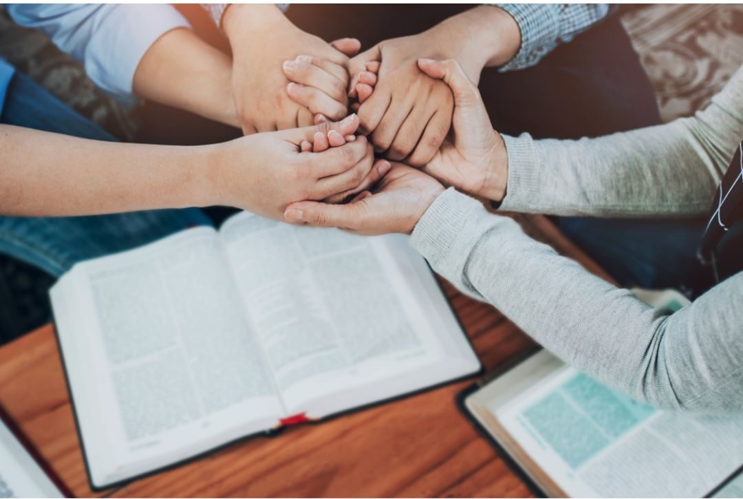 family holding hands in circle over school backpacks praying together