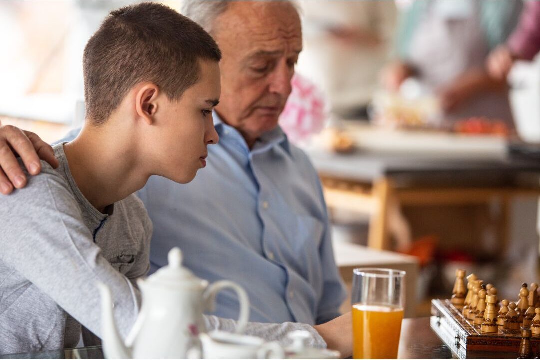 grandfather sitting with teenage grandson sharing wise counsel