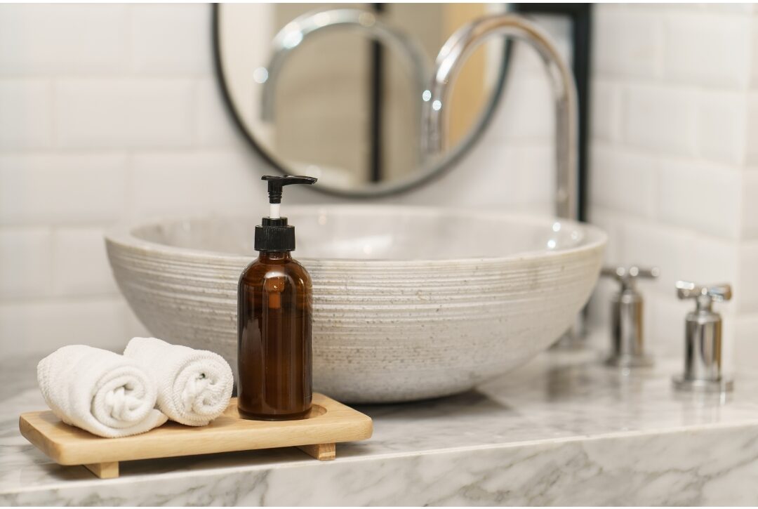 clear amber glass soap pump bottle sitting beside a white bathroom sink