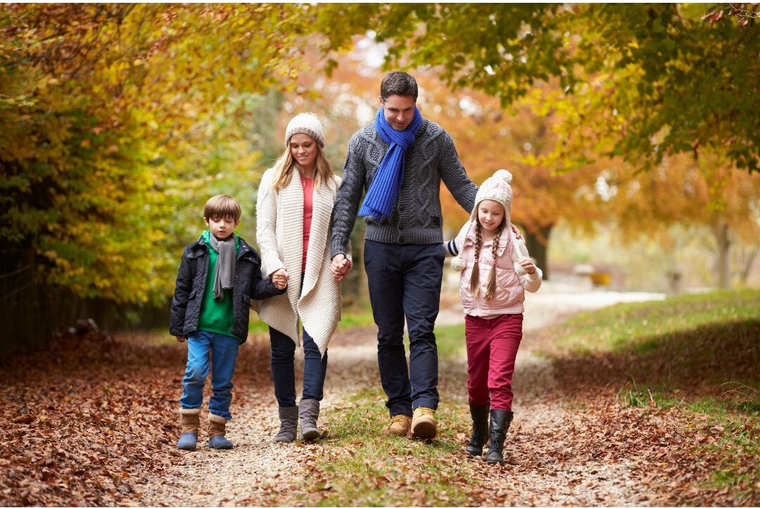 family walking down leaf covered path in evening holding warm glowing lanterns