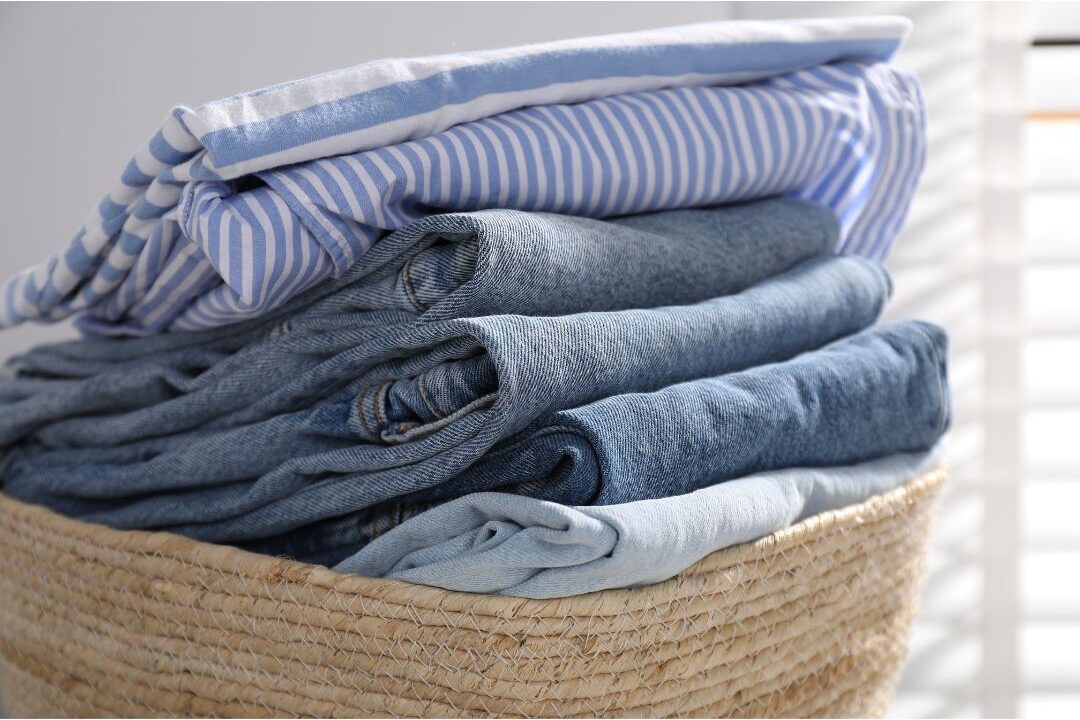 folded pile of clean cotton laundry in woven basket sharing 60 soft life ideas every mom should try