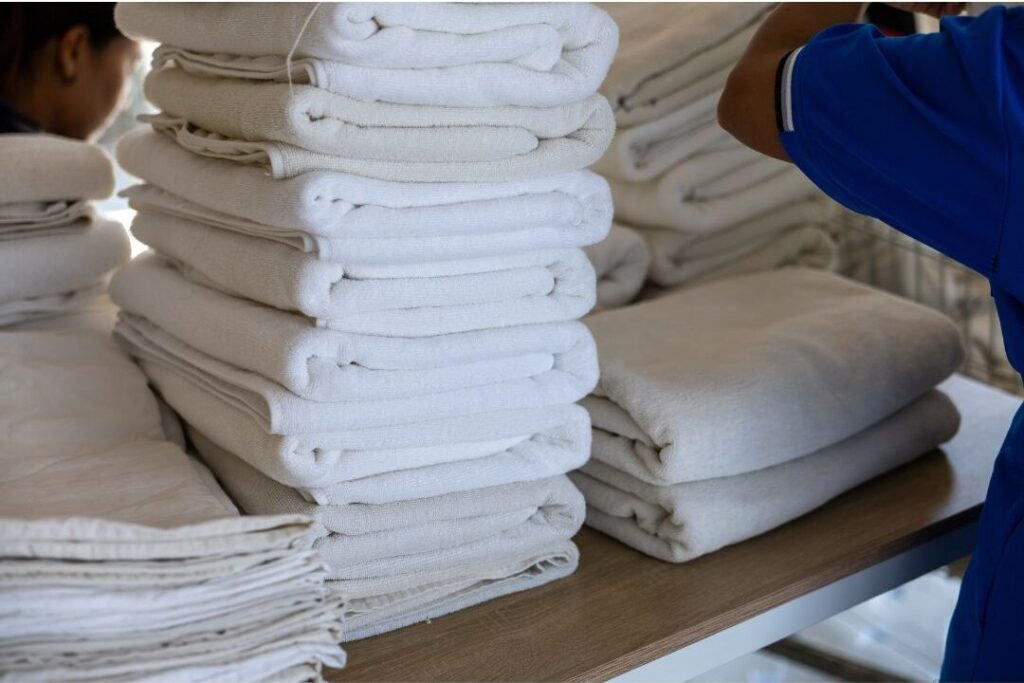 neatly folded pile of white linens on wooden table