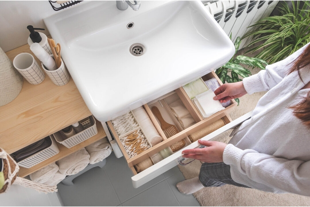 organized bathroom drawer with clear acrylic trays holding toiletries